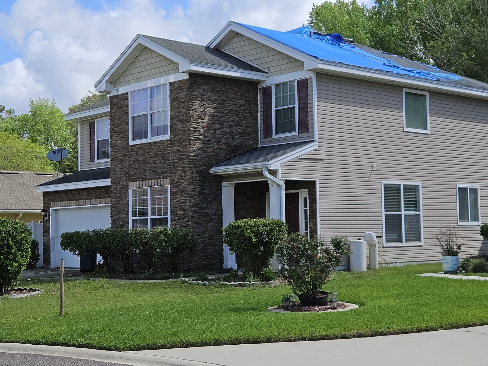 Jacksonville home with storm roof damage covered by a temporary blue tarp